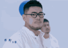 a man wearing glasses and a white jacket stands in front of a blue balloon with chinese writing on it
