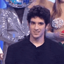 a man in a black suit is standing in front of a mermaid costume .