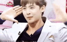 a man in a white jacket salutes with his hands over his ear