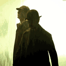 a man in a bowler hat stands next to another man in a trench coat