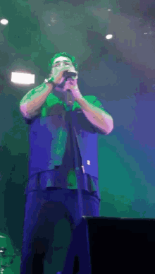 a man singing into a microphone on a stage with green lights behind him