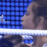 a woman is sitting in a boxing ring with her eyes closed and a rope around her neck .