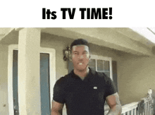 a man in a black shirt is standing in front of a house with the words " it 's tv time " written above him