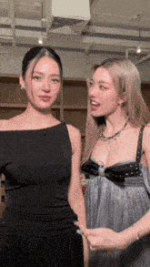 two women standing next to each other with one wearing a black top