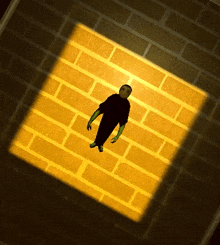a man in a black shirt is standing in front of a brick wall in a dark room