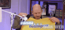 a man is holding a yellow shirt that says awww buttinger dark web on it