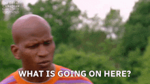 a bald man says what is going on here in front of trees