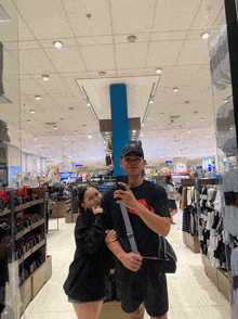 a man taking a picture of a woman in a store with the word calvin klein on his shirt