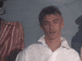 a young man in a white shirt is standing in front of a striped shirt .