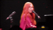 a woman singing into a microphone with her eyes closed