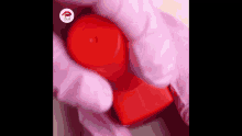 a person wearing pink gloves is holding a red bottle .