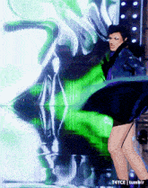 a woman in a blue dress is dancing in front of a green background