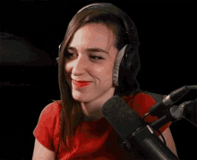 a woman wearing headphones and a red shirt is talking into a microphone