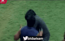 two men are playing tug of war on a field with a twitter logo in the corner