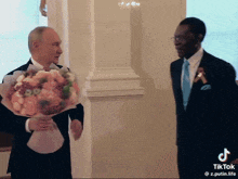 a man holding a bouquet of flowers is standing next to another man