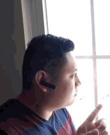 a man wearing headphones looks out a window