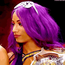 a woman with purple hair is wearing sunglasses and a wrestling championship belt .