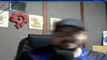 a blurry picture of a man sitting in a chair talking into a microphone