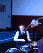 a man is playing drums in a room with an american flag in the background