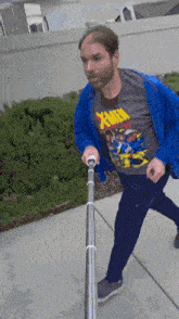 a man wearing a x-men t-shirt is holding onto a pole