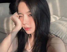 a girl with long black hair is taking a selfie with her hand on her face