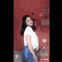 a girl in a white shirt and blue jeans is dancing in a bedroom .