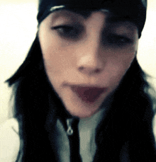 a close up of a woman 's face wearing a black beanie