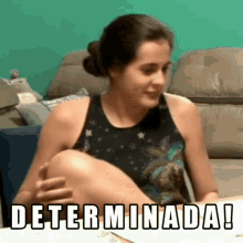 a woman is sitting on a couch with her legs crossed and the words determinada written on the screen