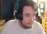 a man wearing headphones and a white shirt is looking at the camera .