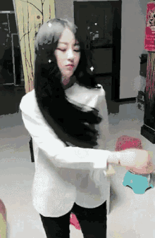 a woman with long black hair is wearing a white shirt