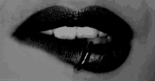 a close up of a woman 's lips with black lipstick and a piercing in her lip .