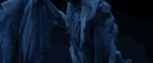 a woman with white hair is wearing a blue dress with her arms outstretched