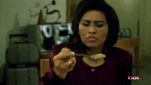 a woman with glasses is holding a spoon in front of a sign that says bull