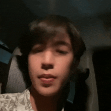 a young man is sitting in the back seat of a car and making a face .