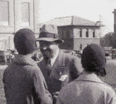 a man wearing a hat is talking to two women