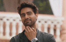 a man with a beard and a watch on his wrist is smiling