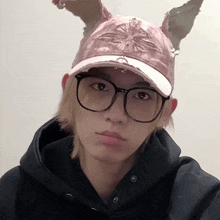 a young man wearing glasses and a pink hat with bunny ears