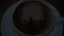 a person 's face is visible in the dark inside of a cup