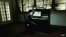 a man playing a piano in a dark room with a rbd.gif watermark