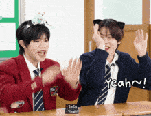 two boys are sitting at a desk with yeah written on the bottom