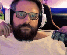 a man with a beard is wearing headphones and glasses while holding a microphone .