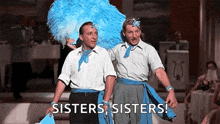 two men are standing next to each other on a stage and they are wearing blue feathers .