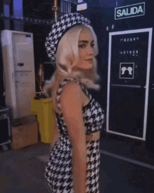 a woman wearing a crop top and skirt is standing in front of a sign that says salida .