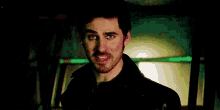 a man with a mustache and beard is smiling in a dark room .