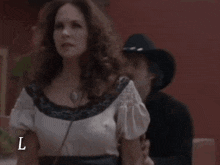 a man in a cowboy hat stands next to a woman in a white dress with the letter l on the bottom