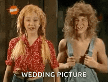 a man and a woman are standing next to each other in overalls .