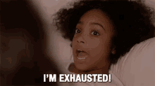 a young girl is laying in bed and saying `` i 'm exhausted ! ''