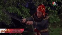 a man in a red hat is holding a large sword in front of a sign that says 7 hd