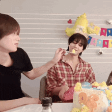 a person is feeding another person a piece of cake in front of a happy birthday banner