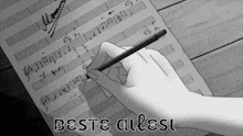 a person is writing on a sheet of music and the words beste allest are visible
